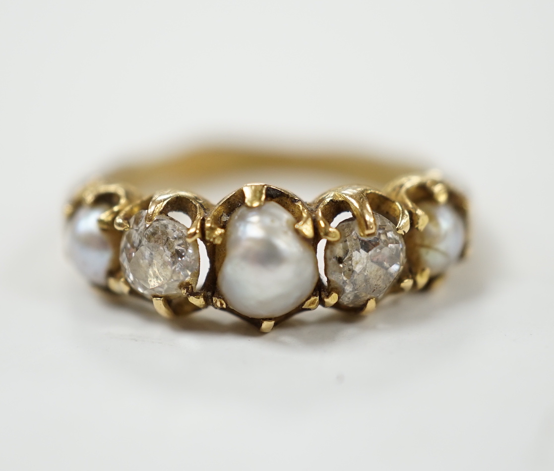 A late Victorian yellow metal and graduated three stone split pearl and two stone diamond set half hoop ring, with unusual wax? insert to the shank, size F, gross weight 3.2 grams.